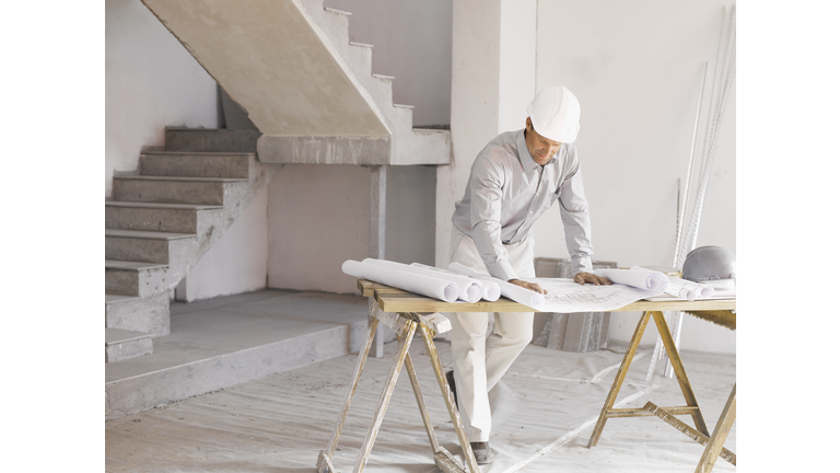 Architect reviewing blueprints at construction site