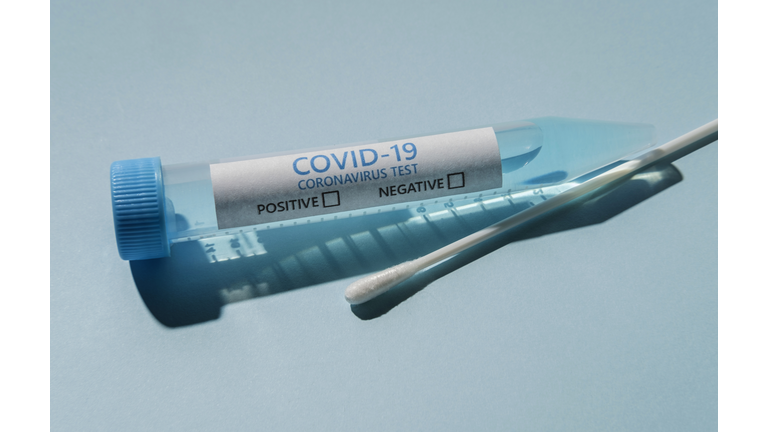 Covid-19 test vial and swab on blue background