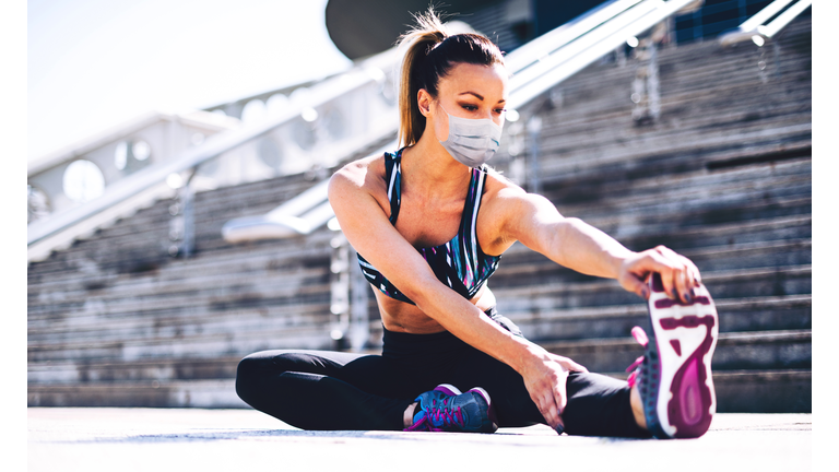 fitness woman stretching outdoor with a face mask