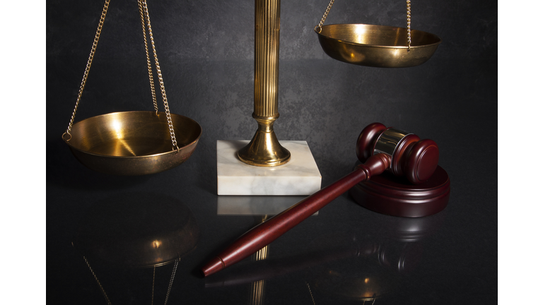 Gavel next to brass scales mounted on marble
