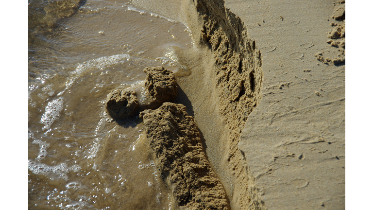 Tide eroding sand from a beach