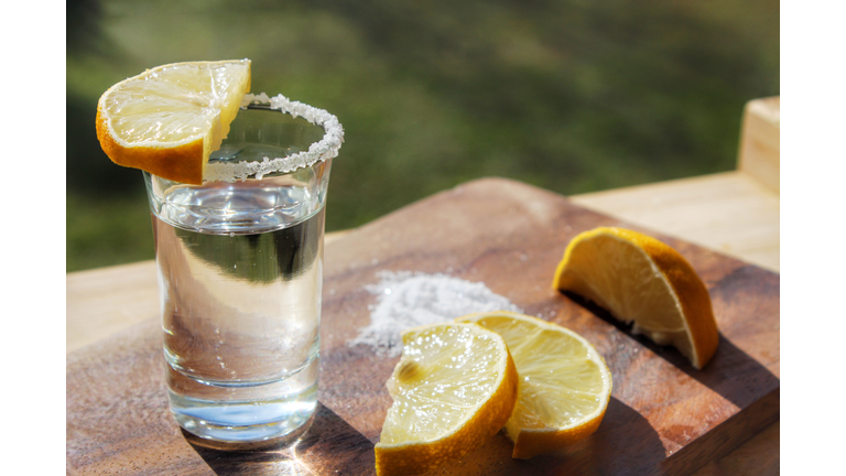 Close-Up Of Tequila Shot With Lemons Slices On Cutting Board