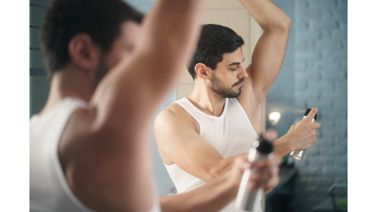 Man Spraying Deodorant On Body At Home