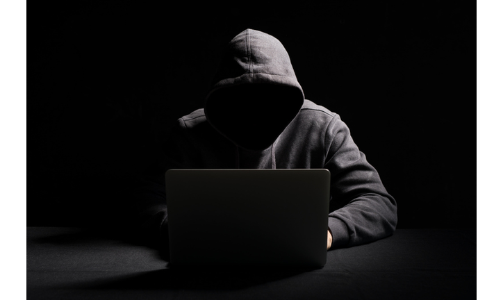 Hacker working on laptop in the dark