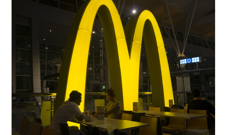 Smiling asian couple eating in McDonalds restaurant