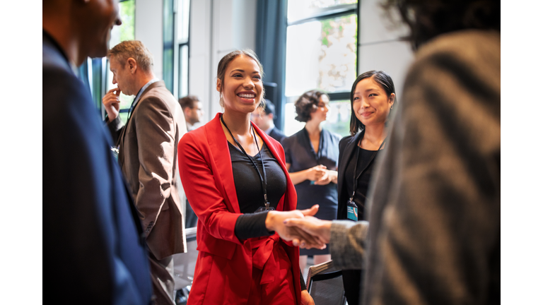 Businesswomen handshaking in auditorium corridor