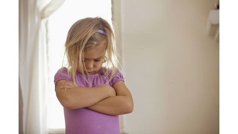 Young girl with head down and arms folded having tantrum