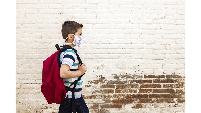 Little boy going to school with protective mask