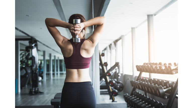 Fitness Asian girl lifting dumbbell at gym.