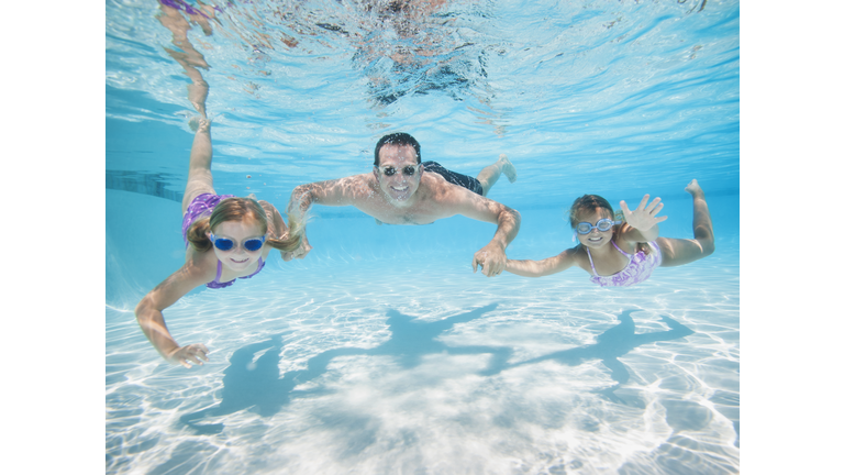 USA, California, Ladera Ranch, Father with two daughters (6-7,8-9) swimming underwater