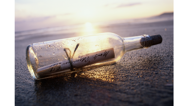 MESSAGE IN BOTTLE ON BEACH AT SUNSET