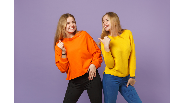 Two laughing joyful young blonde twins sisters girls in vivid co