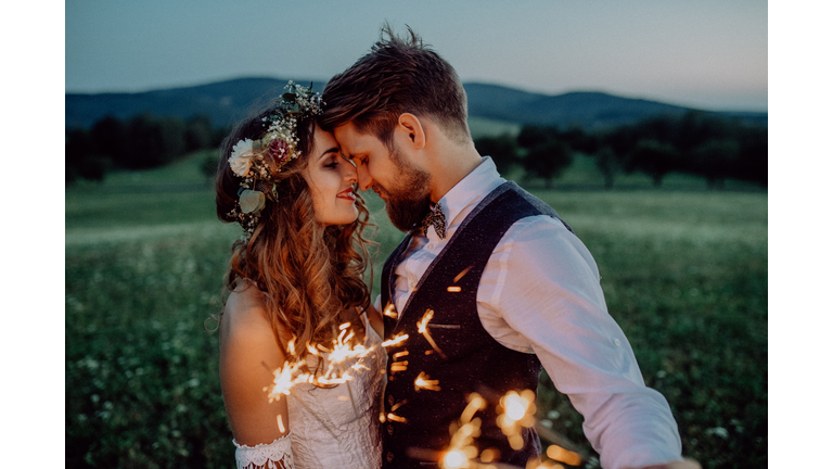 Beautiful bride and groom with sparklers on a meadow.