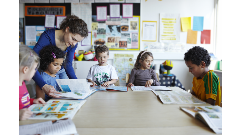 Teacher looking in books with children