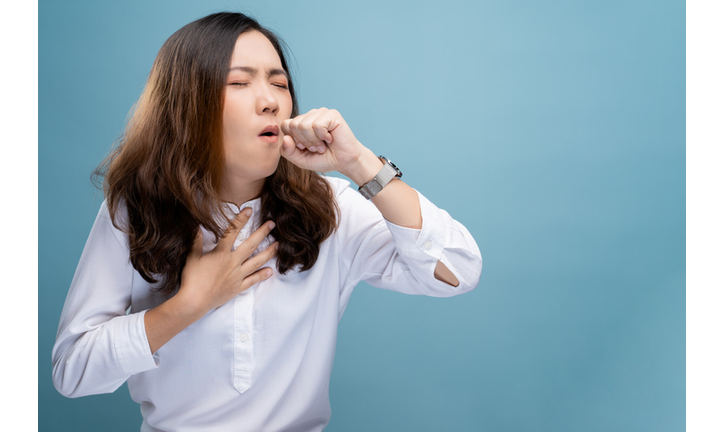 Young Woman Coughing While Standing Against Blue Background