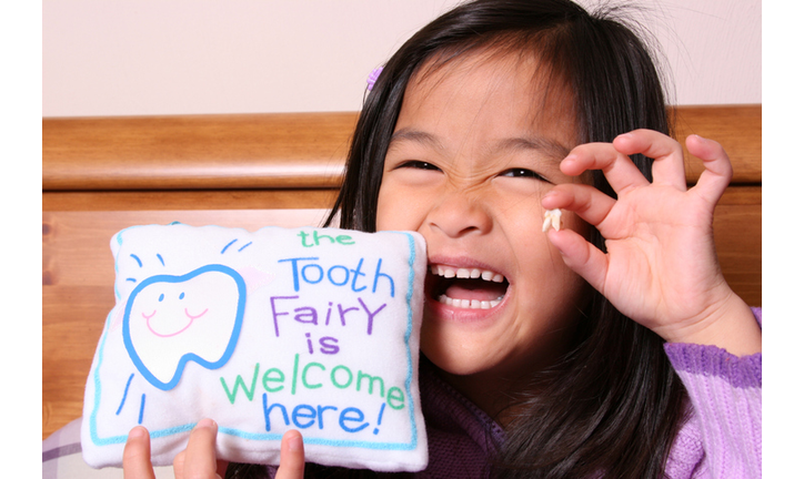 Chinese little girl holding up her tooth