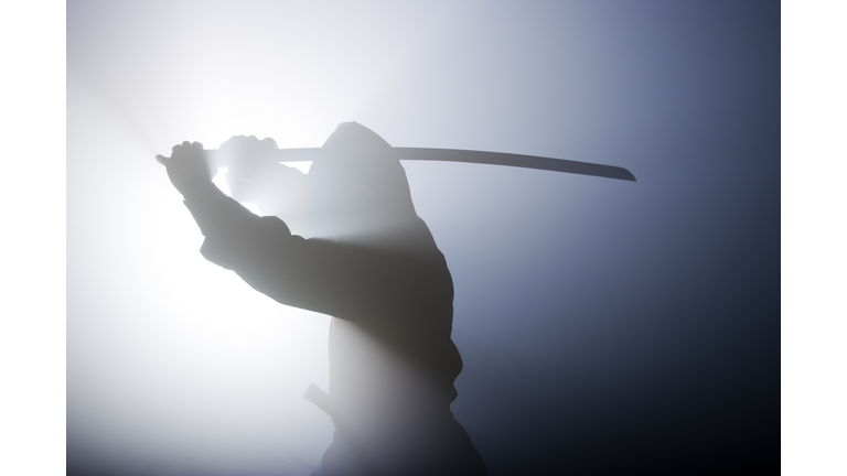 Silhouette of ninja swinging sword in fog
