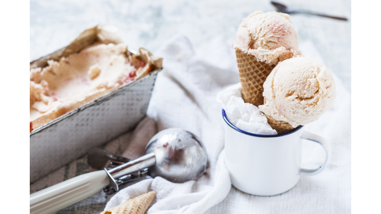 Vanilla icecream with fruit swirl in loaf pan, emaille cup with ice-cream cone and ice scoops, ice cream scoop