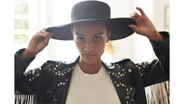 Portrait of confident young woman holding black hat