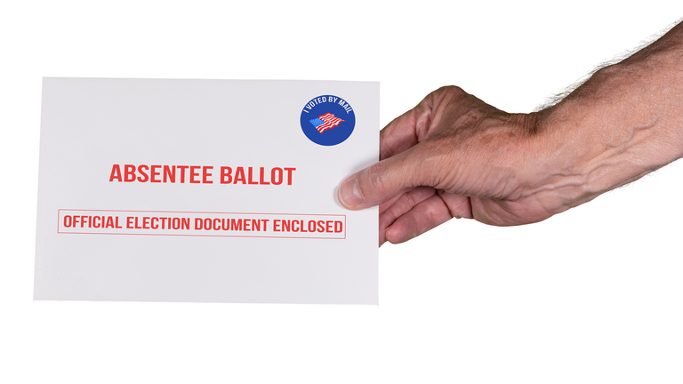 Absentee ballot or vote by mail envelope being handed by senior caucasian hand