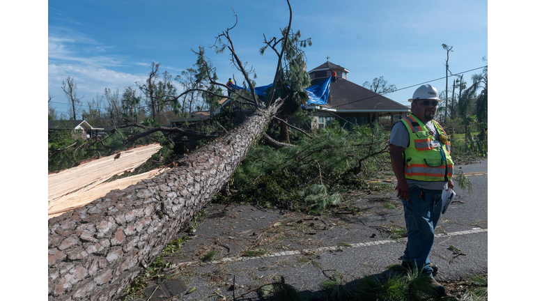 An electric company employee surveys the damage done to the power lines next to a large tree that fell on a house following the passage of hurricane Laura in Lake Charles on August 27, 2020. (Photo by Andrew Caballero-Reynolds/AFP via Getty Images)