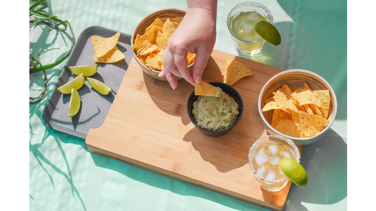 Cropped Hand Of Woman Eating Nacho Chips On Table