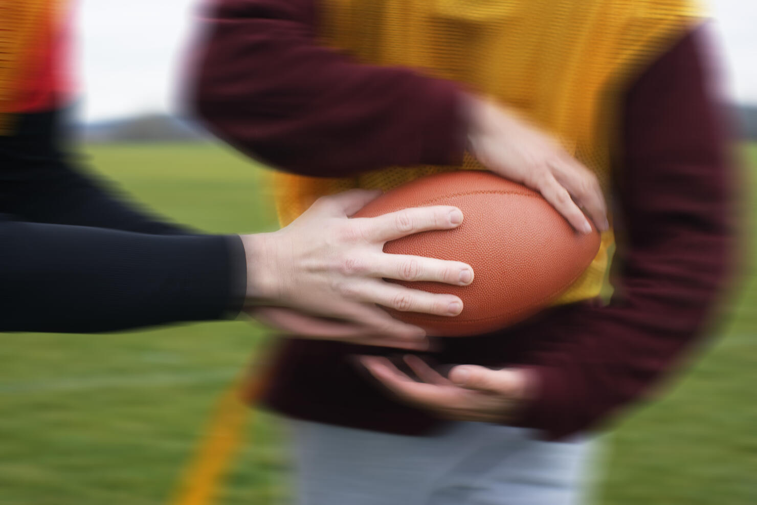 Close up of a hand off of a football in a game of non-contact flag football.