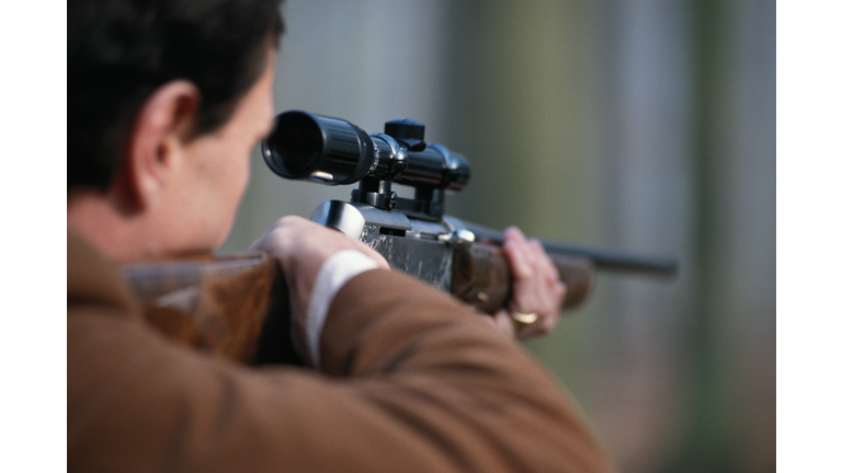 Man aiming rifle, close-up, rear view