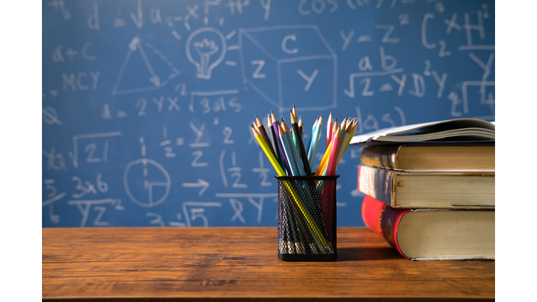 Back to school supplies. Books and blackboard on wooden background