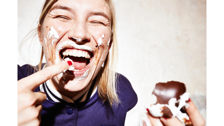 Close up studio shot of young woman with face covered in chocolate marshmallow