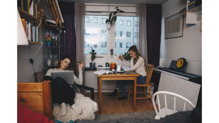 Young female roommates studying together in college dorm room