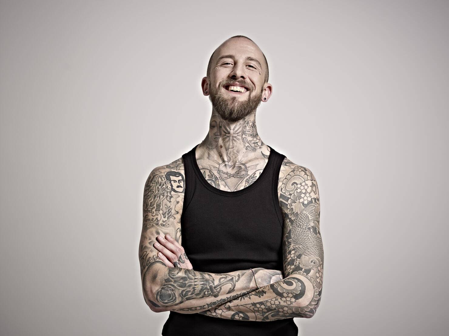 Portrait of bearded man with tattoos laughing.