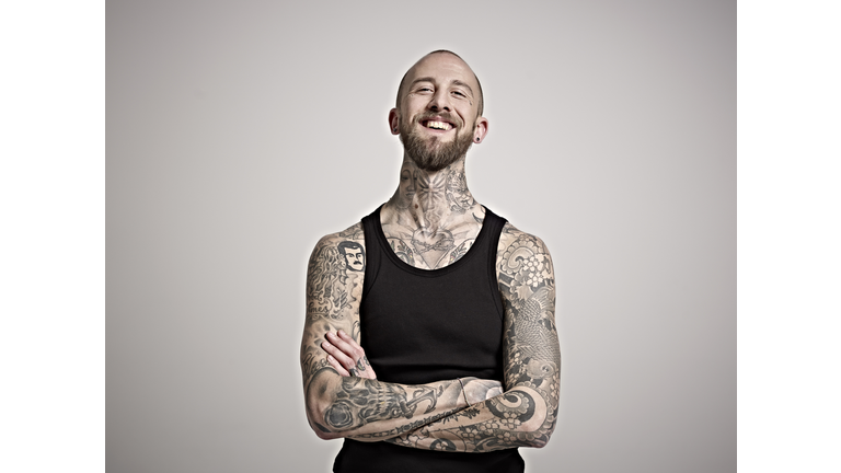 Portrait of bearded man with tattoos laughing.