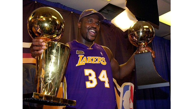 Shaquille O'Neal holds the MVP trophy (R) and the