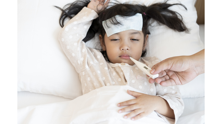 Medical check up and treatment concept. Mother is measure the temperature of little Asian kid girl. Sick child with fever and illness in bed.