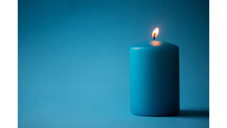 Close-Up Of Illuminated Candle Against Blue Background