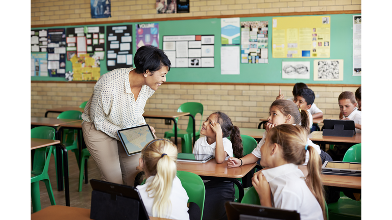 Teacher interacting with kids in class with tablet