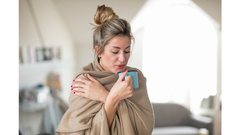 Woman Wrapped Having Drink While Standing At Home