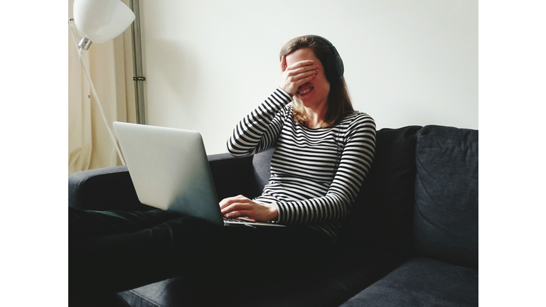 Happy Woman Covering Eyes While Video Chatting Through Laptop At Home