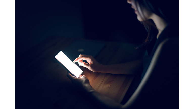 Close up of woman using smartphone in darkness