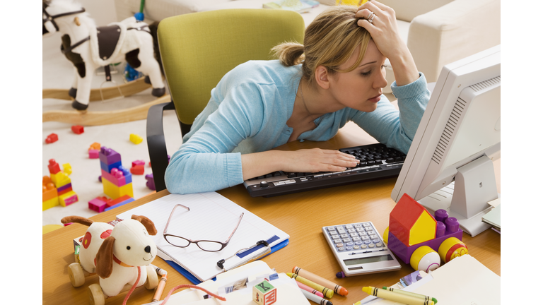 Frustrated Hispanic woman at desk surrounded by toys