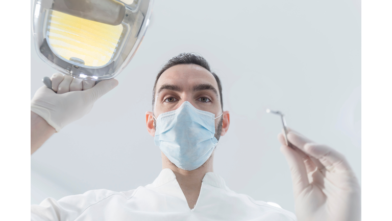 Low Angle Portrait Of Dentist Holding Medical Equipment In Hospital