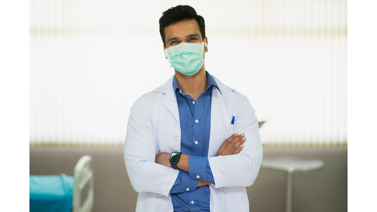 Happy doctor asian man smile under face mask standing at room hospital ward