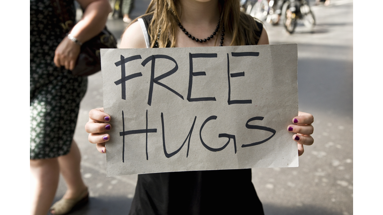 A young woman holding a sign saying Free Hugs