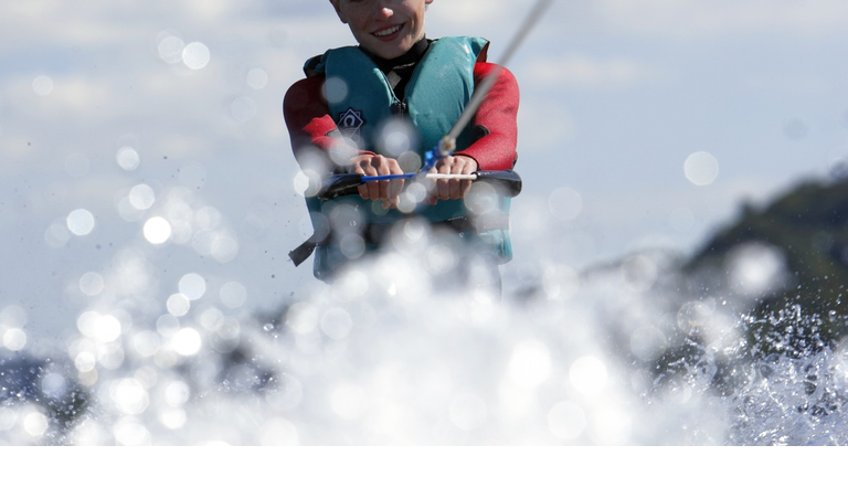 Teenage boy (13-15) waterskiing, smiling