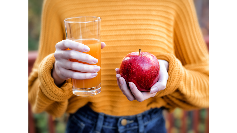 Young woman holding glass of apple juice and fresh apple