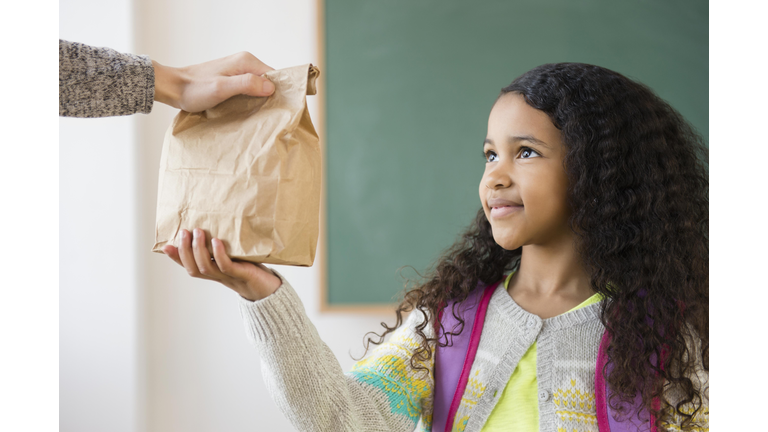 Student taking brown bag lunch in classroom