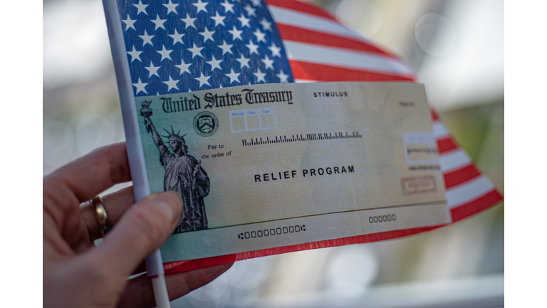 COVID-19 economic Stimulus check on blurred USA flag background. Relief program concept.