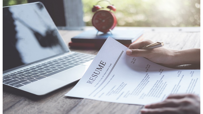 Business man review his resume application on desk, laptop computer, job seeker