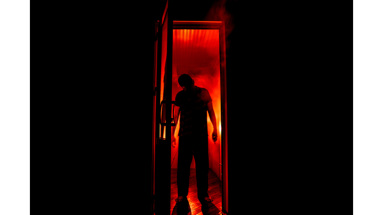 Silhouette of an unknown shadow figure on a door through a closed glass door. The silhouette of a human in front of a window at night. Scary scene halloween concept